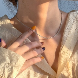 Detailed view of shimmering S925 sterling silver snake chain necklace on woman collarbone