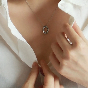 Detail of silver twisted oval hollow pendant necklace worn with a white shirt