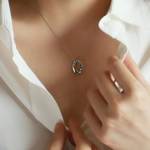 Close-up of a silver-toned oval hollow pendant necklace worn on a woman's neck