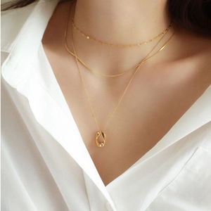 Close-up of layered gold necklaces with oval pendant on a white shirt model