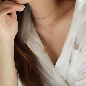 Detailed close-up of triple-layered gold necklaces with a twisted oval pendant on a model