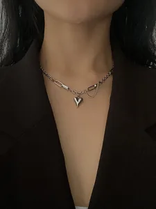 Detail of silver heart pendant with mixed link chain on black blazer outfit