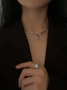 Close-up of asymmetric 925 sterling silver chain with heart pendant and industrial ring