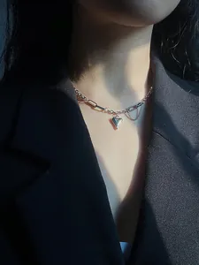 Detail view of silver heart pendant with layered chain on black suit jacket