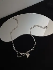Detail of silver heart pendant with mixed link chain and lobster clasp on dark mirror