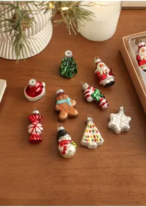 Set of 9 colorful glass Christmas ornaments featuring Santa and snowman on a wooden table