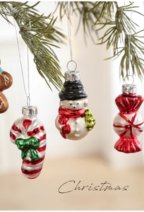 Detailed view of candy cane and snowman glass ornaments hanging on a Christmas tree