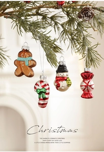Detailed view of glossy gingerbread man and snowman ornaments hanging on a pine branch