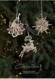 Détails de suspensions paon, flocon et renne à paillettes dorées sur sapin de Noël