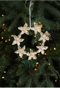 Gros plan d'une couronne de Noël dorée avec des paillettes et un ruban blanc soyeux