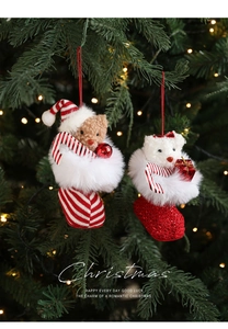Close-up of plush Christmas bear charms in red and white knit boots on a festive tree