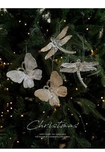 Close-up of glittery butterfly and dragonfly ornaments hanging on a Christmas tree