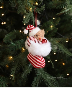 Close-up of a plush Christmas bear in a striped stocking hanging on a festive Xmas tree