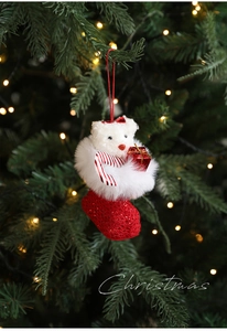 Plush Christmas teddy bear in a red knit stocking hanging on a decorated tree branch