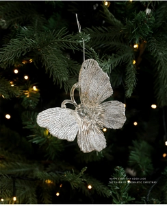 Sparkling silver butterfly ornament with glitter hanging on a festive Christmas tree branch