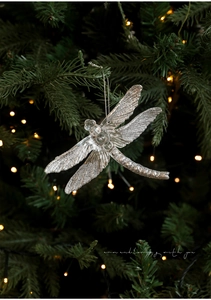 Detail of dragonfly Christmas ornament with silver glitter on clear wings hanging on tree