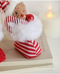 Close-up of a plush teddy bear inside a red and white knitted Christmas stocking decoration