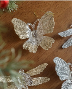 Close-up of glittery butterfly ornaments with hanging cords on a wood background