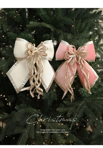 Close-up of velvet Christmas bows with gold glitter edges hanging on a warm lit tree
