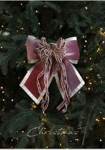 Close-up of luxury burgundy velvet Christmas bow with gold lace on a lit festive tree