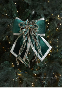 Detail of dark green velvet Christmas bow with silver edges on a lit tree branch