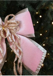 Close-up of pink velvet Christmas bow with gold glitter edges on a holiday tree