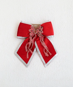 Detail of red velvet Christmas bow pendant with silver edges and festive glitter accents