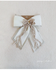 Detailed view of elegant white fabric Christmas bow with silver trim and gold glitter center