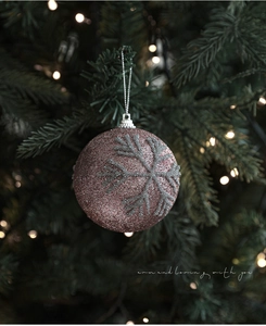 Détail d'une boule de Noël rose pailletée avec flocon de perles sur le sapin
