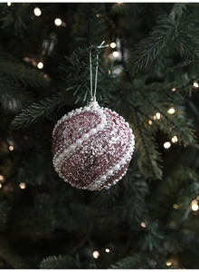 Boule de Noël rose avec paillettes et perles blanches suspendue à un sapin festif