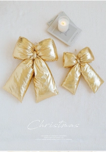 Close-up of golden metallic Christmas bow set on white plush carpet with festive candles