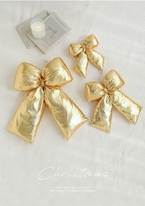 Three-piece set of shiny golden Christmas bows in different sizes with hanging strings