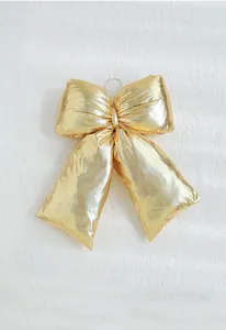 Detailed view of glossy gold Christmas bow with fine texture on soft white fur backdrop