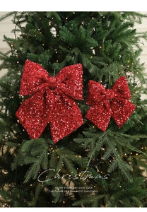 Detail der roten Pailletten-Weihnachtsschleifen mit warmem Lichterketten-Hintergrund