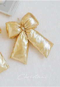 Close-up of golden Christmas bow with metallic sheen and rich texture on plush rug