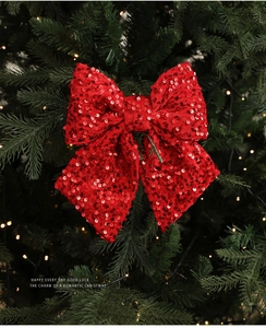 Nahaufnahme einer festlichen roten Pailletten-Stoffschleife am grünen Weihnachtsbaum