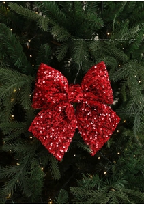 Detail eines roten Pailletten-Weihnachtsschleifen-Ornaments an einem grünen Baum