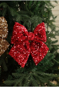Funkelnde rote Pailletten-Schleife am Weihnachtsbaum mit warmen Lichtern dekoriert