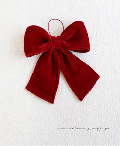 Detail of red velvet Christmas bow with elastic band showing rich texture and soft luster