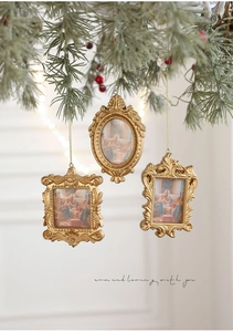 Golden Baroque mini photo frames hanging on a Christmas tree branch as festive ornaments
