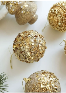Detail of golden Christmas baubles with glitter, sequins and star patterns on white background