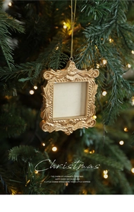 Close-up of vintage golden baroque mini photo frame hanging on a green Christmas tree
