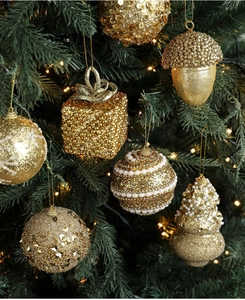 Detail of luxury gold Christmas ornaments with glitter and pearls on a green tree
