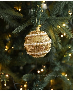 Golden Christmas ball with pearls and glitter hanging on tree, detail of festive ornaments