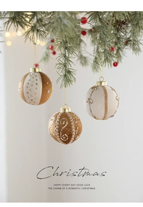 Close-up of 8cm brown fabric Christmas balls with golden embroidery on pine branches