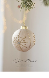 Detail of 8cm beige velvet Christmas ball with gold glitter snowflake on pine branch