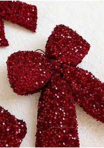 Close-up of a burgundy velvet Christmas bow with sequins on a white plush surface