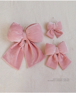 Ensemble détaillé de trois nœuds de Noël en velours rose de différentes tailles sur tissu