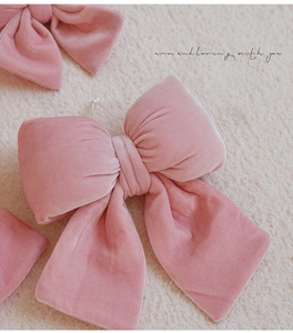 Détail de nœuds de Noël en velours rose avec texture douce sur fond en peluche blanche