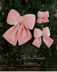Nœuds de Noël en velours rose de tailles variées sur un sapin illuminé